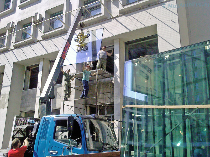 Монтаж витринного стеклопакета с помощью манипулятора с вакуумной присоской на высоте второго этажа.